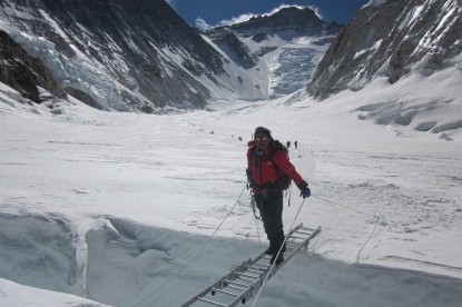 Sherpa climbers crossing the ladder over the crevasses.